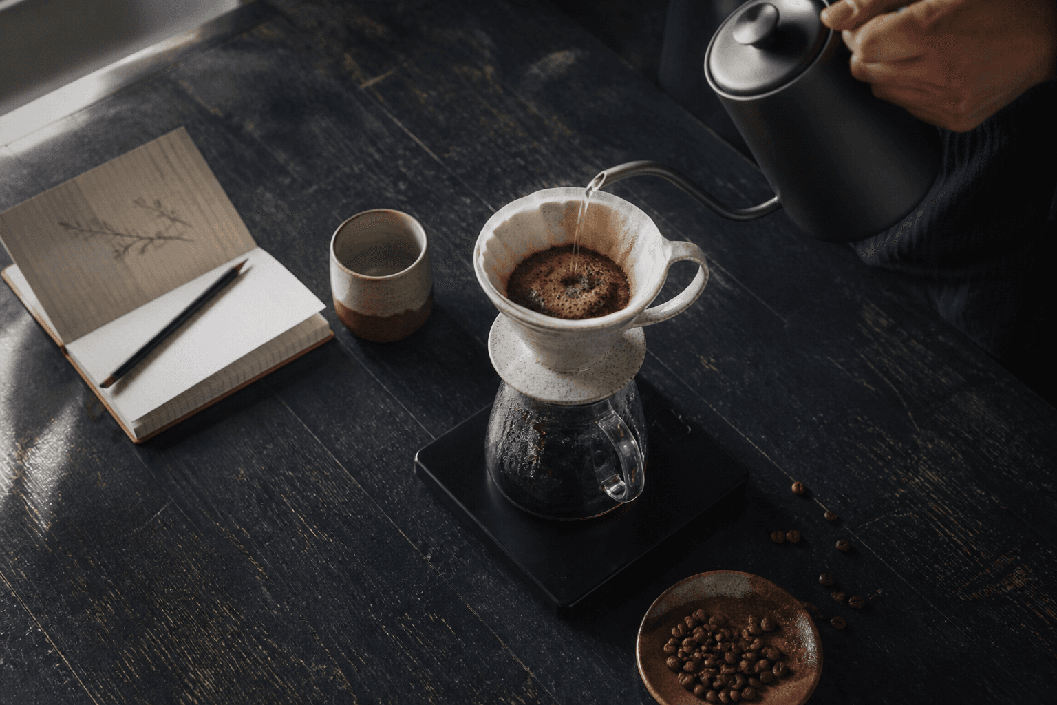 A pour-over coffee being brewed on a dark wooden table